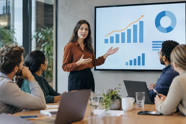 A business analyst explains a chart to a small team.